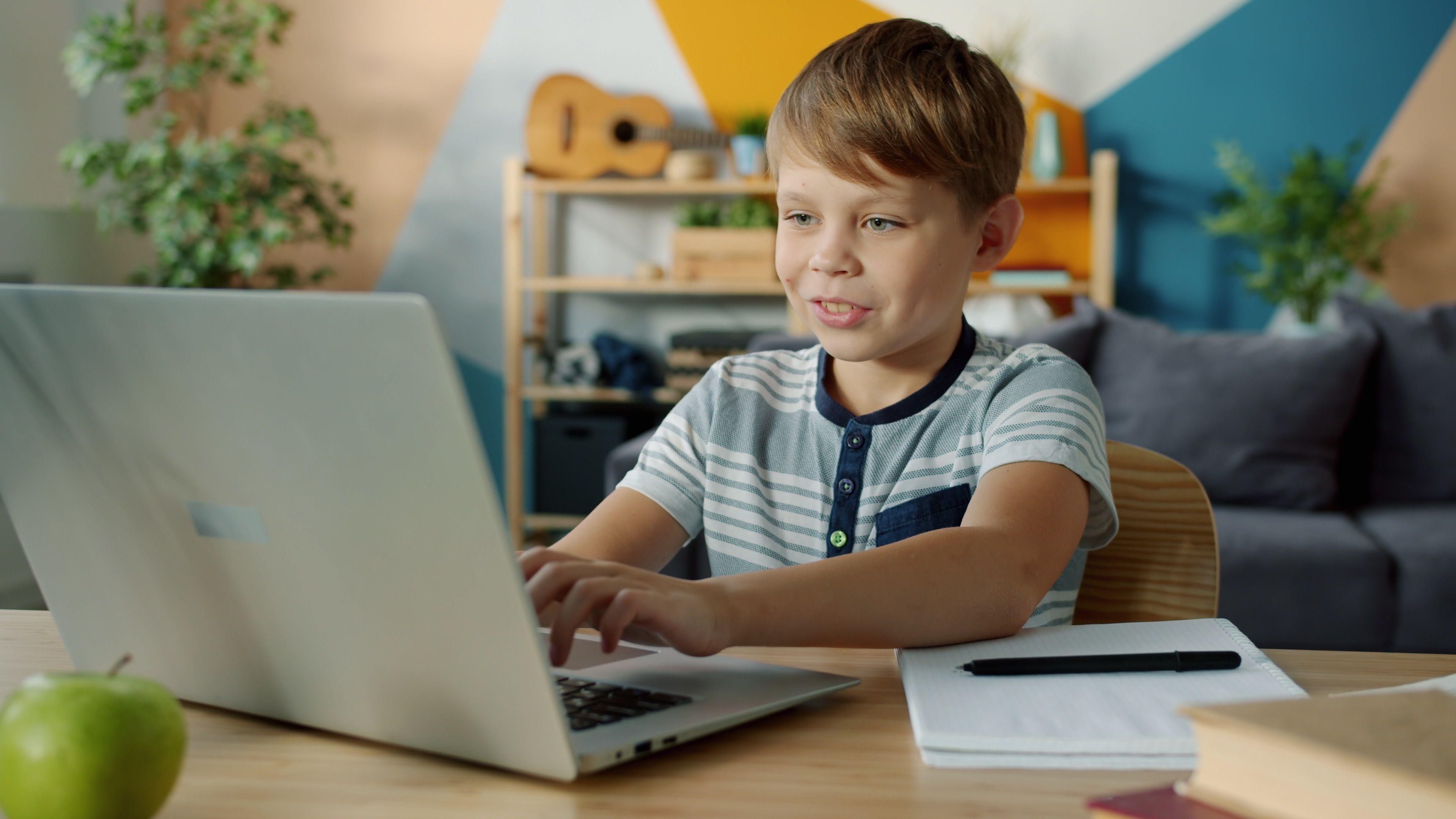 Leerling werkt geconcentreerd achter een laptop in een lichte, moderne leeromgeving